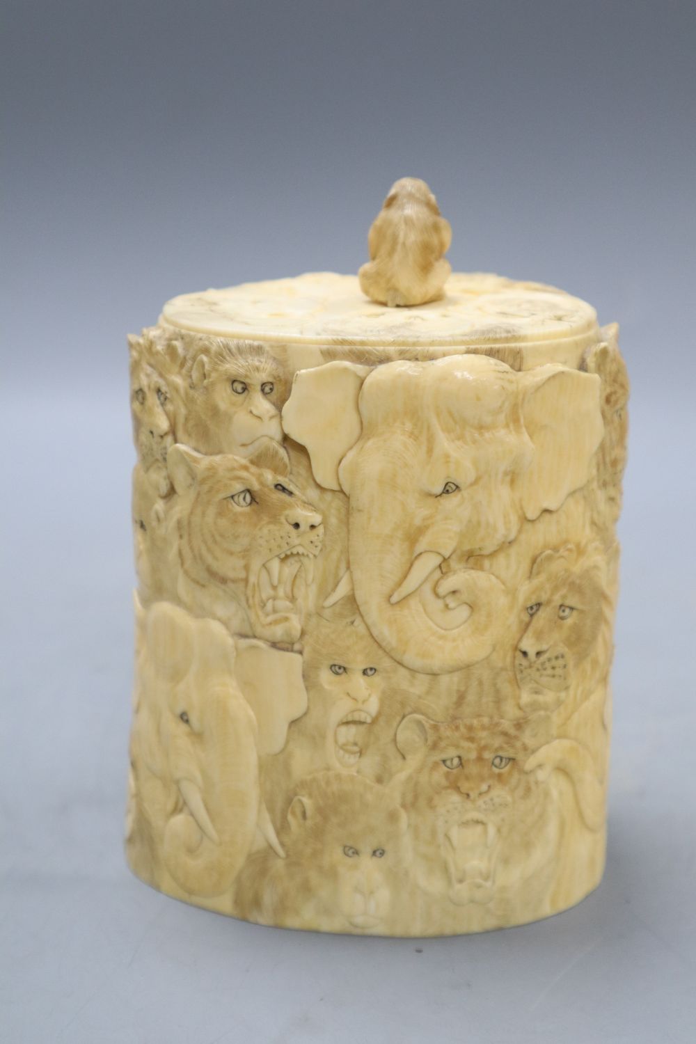 A Japanese ivory box and cover, Meiji Period, carved with elephants, lions, monkeys, etc. (lacking base), overall height including lid